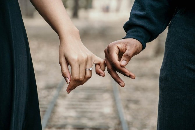 Two people holding hands wearing engagement ring