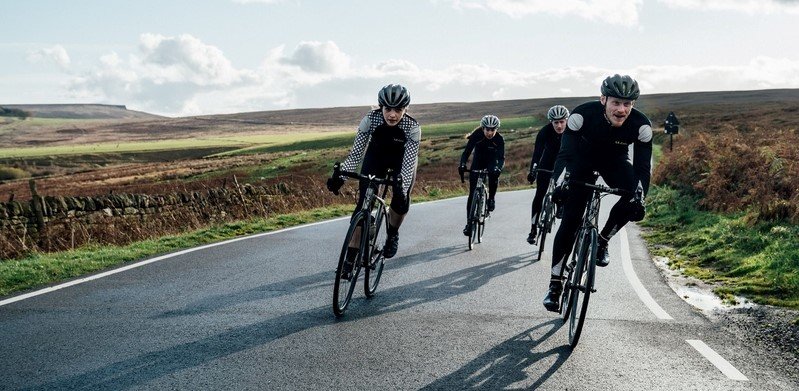 Le Col cycling page banner showing a group of people cycling in a remote location