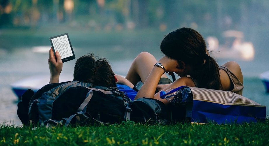 couple using kobo ereader lying on grass